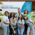 Center for Health Progress staff pose outdoors under CHP banner